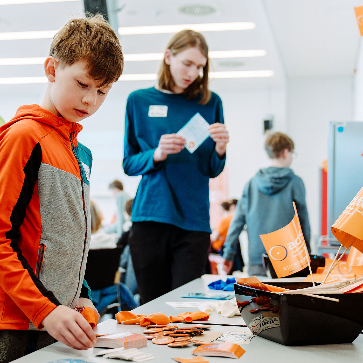 Teilnehmende bei der Landesjugendversammlung 2026 begutachten am Goodie-Tisch Sticker, Buttons, Flyer und weitere Kleinigkeiten.