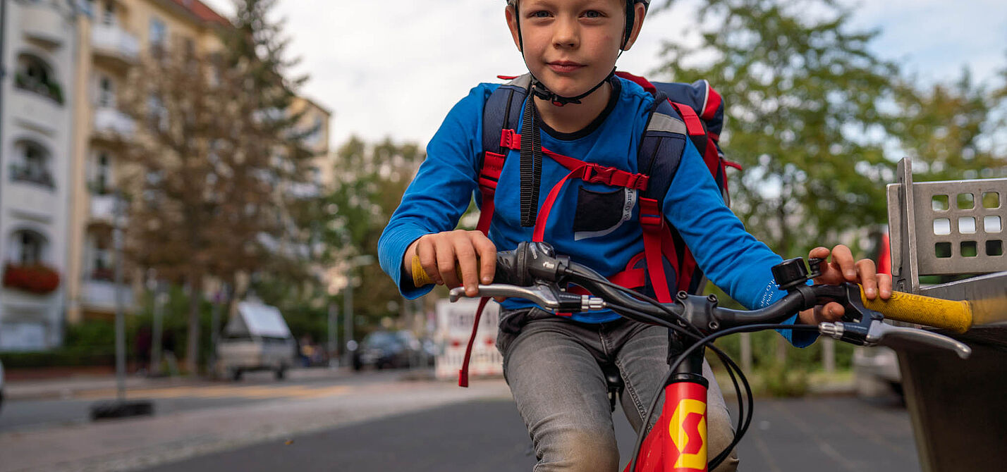 Junge mit Schulranzen auf dem Rad Ein Junge mit Schulranzen fährt mit dem Rad.