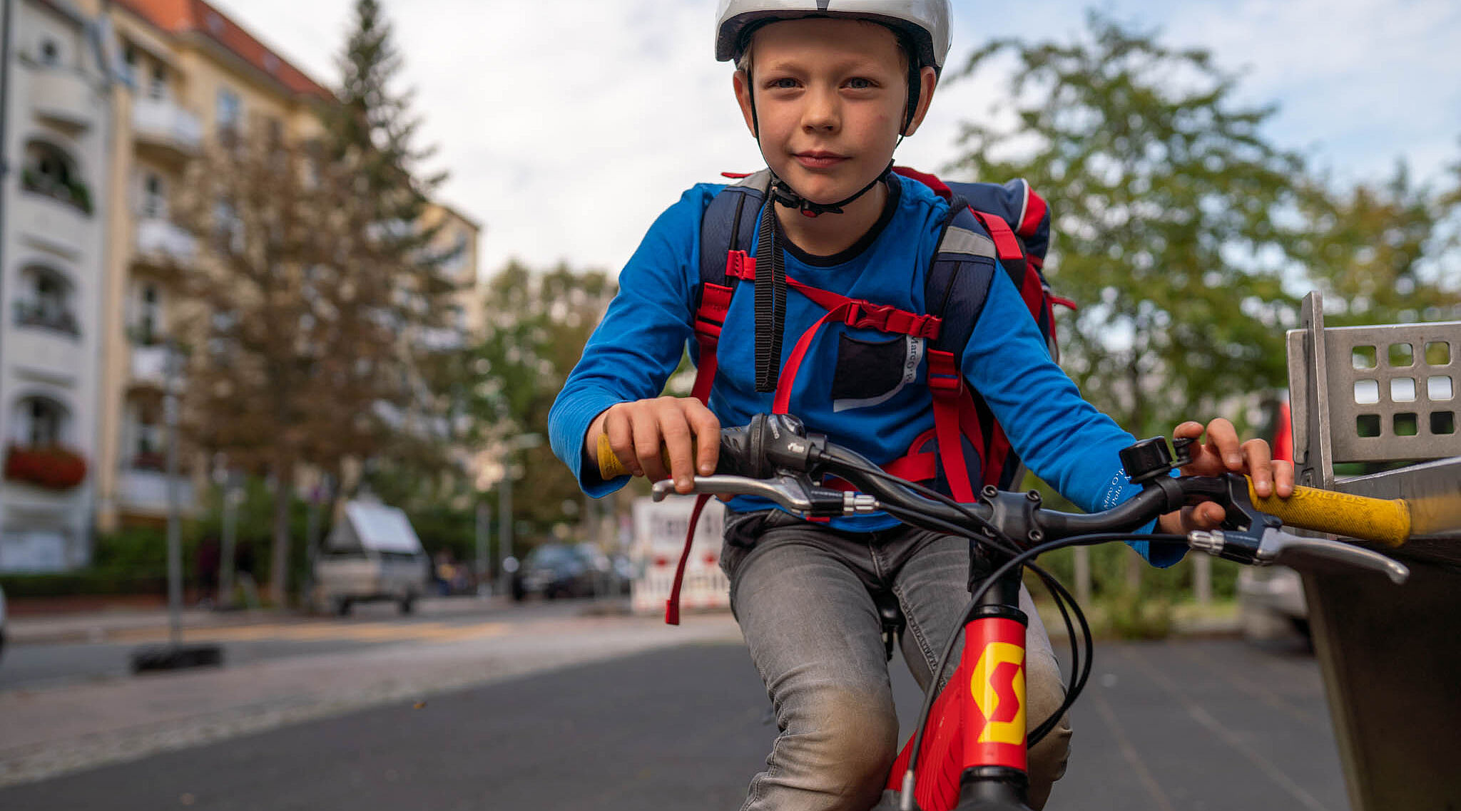 Ein Junge mit Schulranzen fährt mit dem Rad.