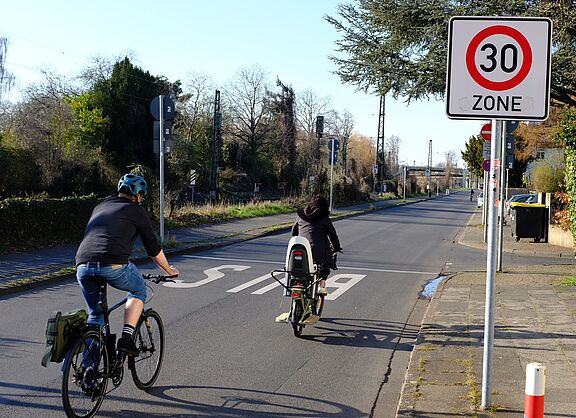 Zwei Radfahrer fahren an einem Tempo 30 Schild vorbei. 