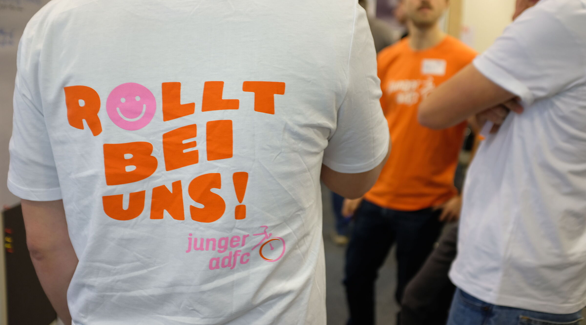 Ein Mensch mit einem T-Shirt, auf dem hinten der Spruch "Rollt bei uns!" steht.
