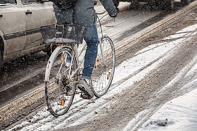 Ein Radfahrer fährt auf einem ungeräumten Radweg durch Schnee.