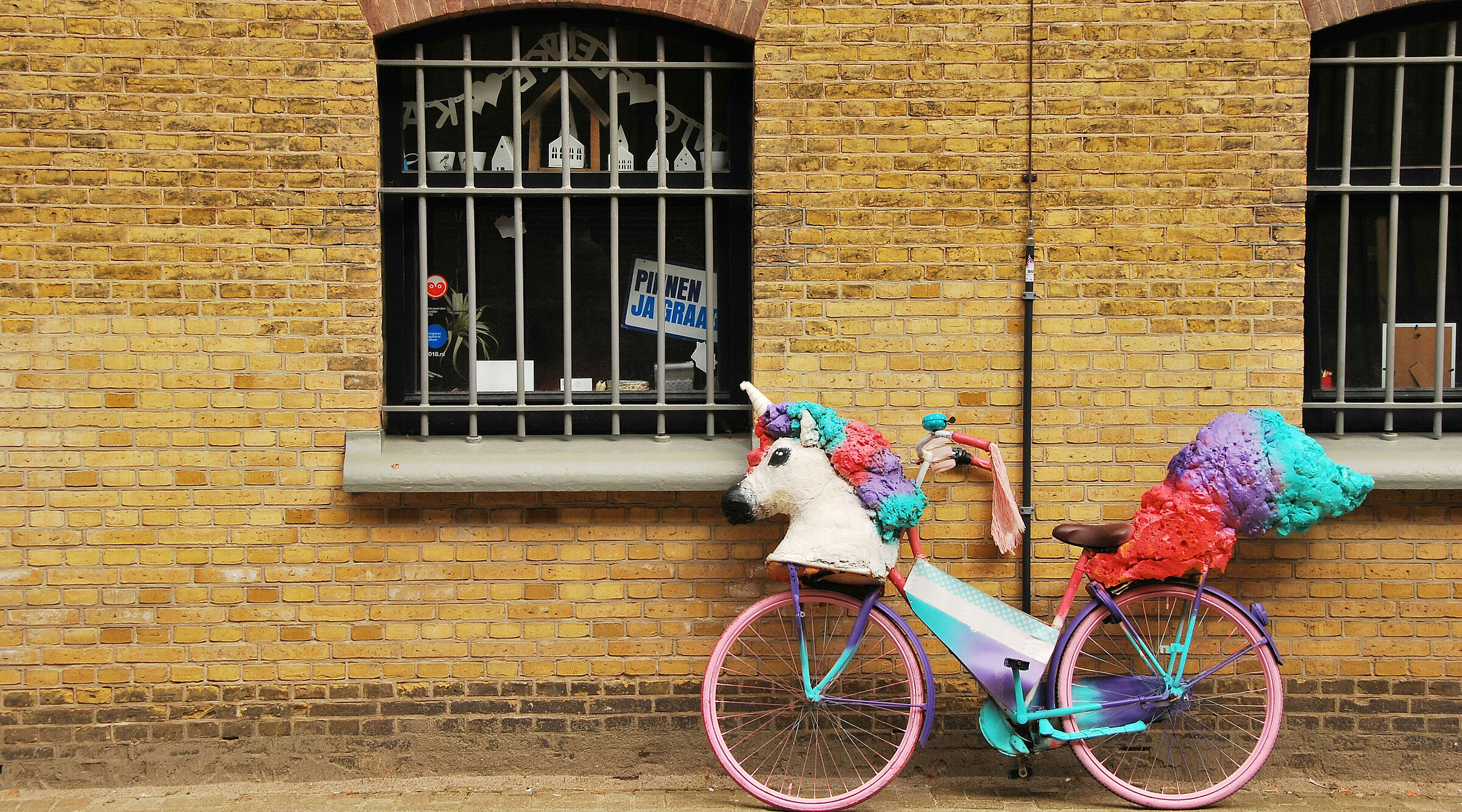 Ein Fahrrad, an dem aus Pappmache ein Einhorn-Kopf und Einhorn-Schweif befestigt sind.