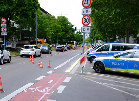 Ein schmaler Radfahrstreifen an einer viel befahrenen Straße. Die Verkehrssituation scheint wenig übersichtlich zu sein. 