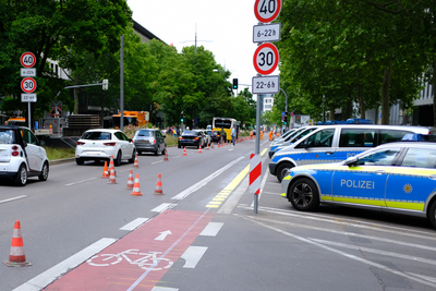Ein schmaler Radfahrstreifen an einer viel befahrenen Straße. Die Verkehrssituation scheint wenig übersichtlich zu sein. 