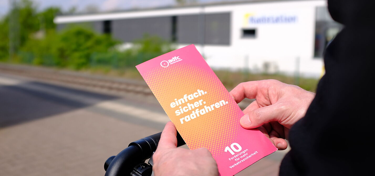 Eine Person hält einen Flyer in den Händen.