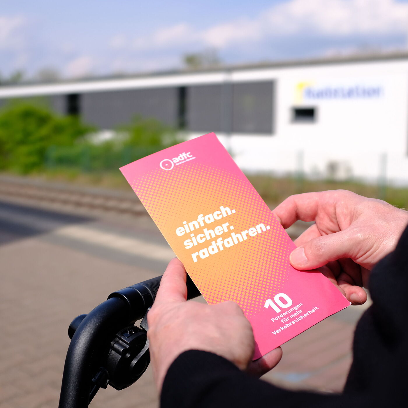 Eine Person hält einen Flyer in den Händen.