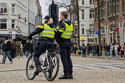 Eine Polizistin auf dem Fahrrad und ein Polizist beobachten eine Fußgängerzone in einer niederländischen Stadt. Die Etablierung von Fahrradstaffeln in der Polizei in NRW ist eine der 10 Forderungen des ADFC NRW im Rahmen der Kampagne "einfach. sicher. radfahren.".