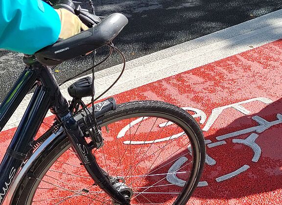Neu markierter Radfahrstreifen mit flächiger Roteinfärbung. Man sieht auch einen Fahrradlenker.