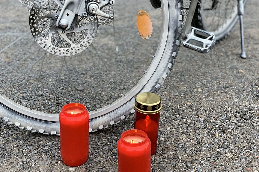 Ein weißes Ghostbike und brennende Kerzen.  Ein weißes Ghostbike und brennende Kerzen.