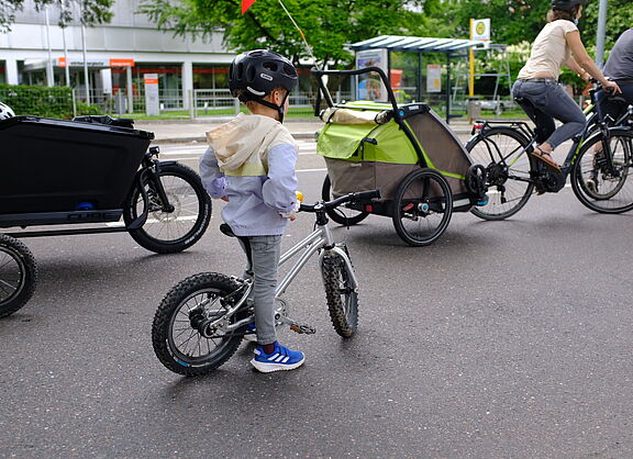 Ein Kind mit Fahrrad und Eltern mit Radanhänger und Lanstenrad sind auf dem Bild zu sehen.