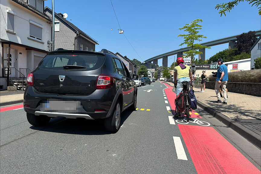 Auto überholt Radfahrer Eine Person im Auto überholt einen Radfahrer in Siegen-Eiserfeld auf der Eiserfelder Straße.
