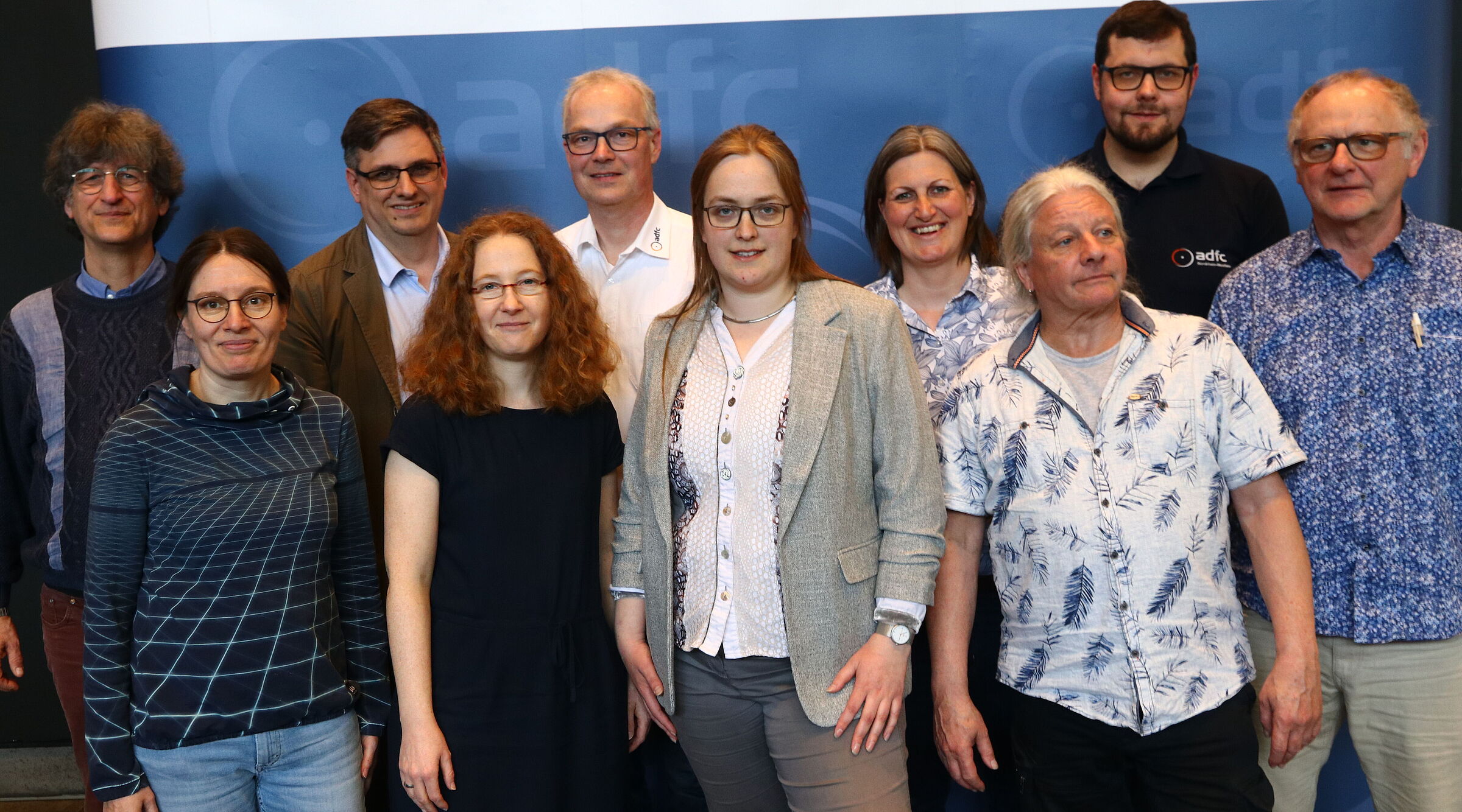 Der Landesvorstand des ADFC NRW, bestehend aus 10 Personen, steht vor einer Stellwand mit ADFC-NRW-Branding.