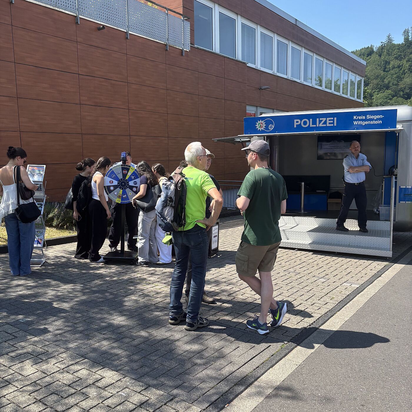 Am Infostand der Polizei in Siegen-Eiserfeld informiert sich eine Gruppe Schüler:innen über Radverkehrssicherheit.