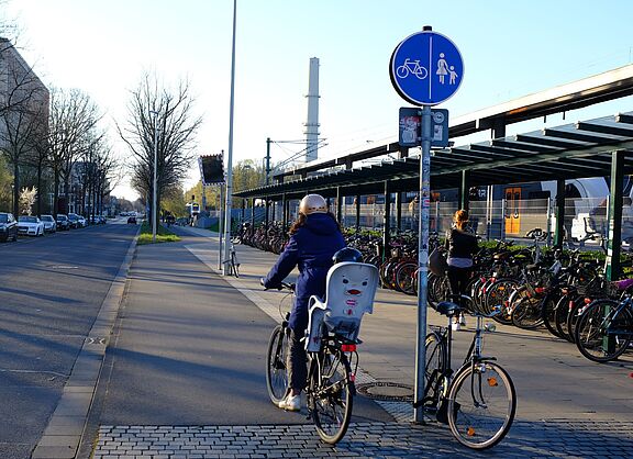Bahnhalt, Regionalbahn, Radabstellanlage und eine Radfahrerin. 
